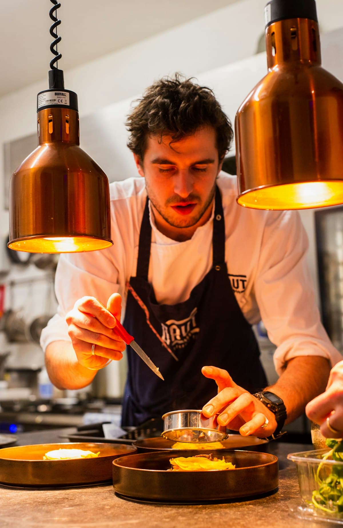 Plating at the pass, the last check before a dish leaves the kitchen